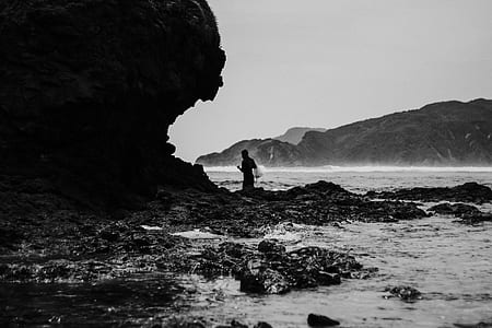 grayscale photo of person standing near body of water thumbnail