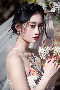 woman holding white petaled flowers wearing spaghetti strap top thumbnail