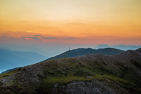 green grass filled mountain under orange and blue sky thumbnail