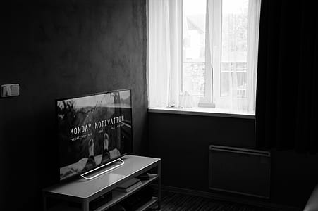 Gray Scale Photo of Flat Screen Tv on Top of Wooden Tv Rack thumbnail