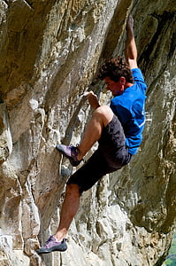 man climbing on rock formation on focus photo thumbnail