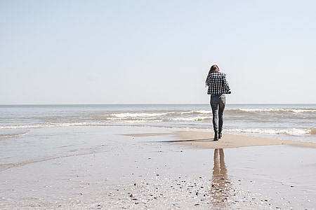 woman in white and black blazer walking on seashore thumbnail