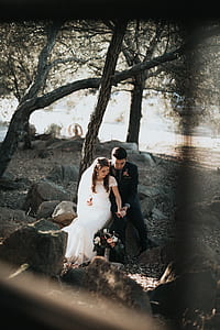 bride and groom sitting on gray rock thumbnail