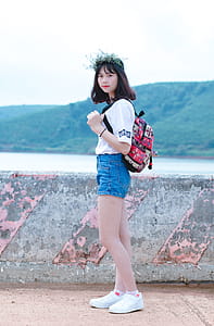 Photo Of Woman With Red And Black Backpack Standing Near Concrete Fence thumbnail
