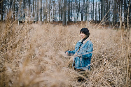 woman in blue chambray jacket stand on brown grass thumbnail