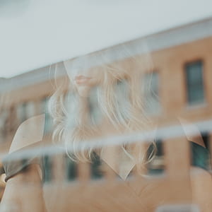 woman reflecting on clear glass window thumbnail