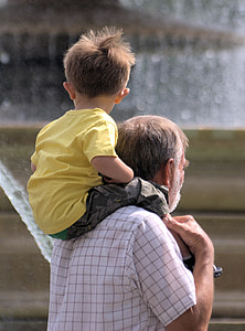 toddler wearing yellow T-shirt carried by man during daytime thumbnail