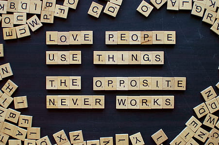 brown wooden scrabble chips forming love people use things the opposite never and works letters thumbnail