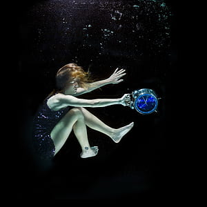 woman carrying blue and gray alarm clock sinking in water thumbnail