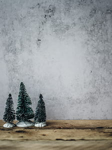 three miniature Christmas trees on top of brown wooden table thumbnail