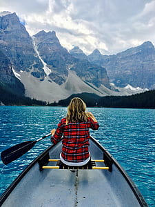woman in boat holding paddle background of snow capped mountain thumbnail
