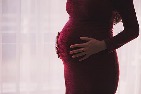 pregnant woman holding her tummy near window thumbnail