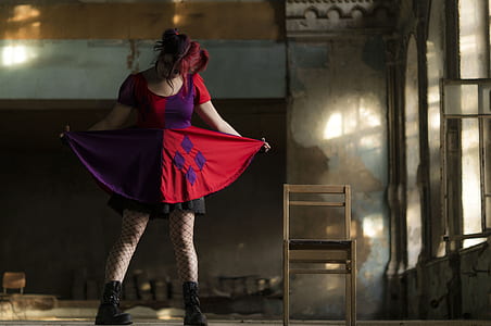 woman in Harley Quinn costume standing beside brown wooden chair thumbnail