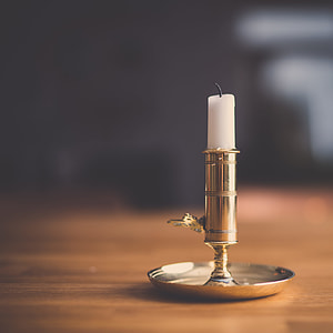 shallow focus photography of white candle in gold candle holder thumbnail