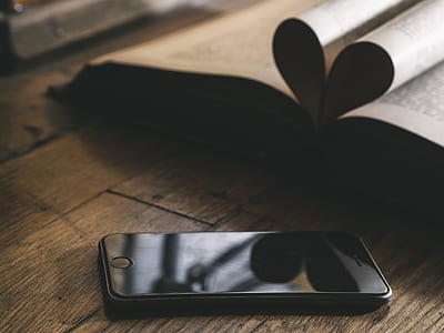 post-2014 black iPhone beside book on top of brown wooden table thumbnail