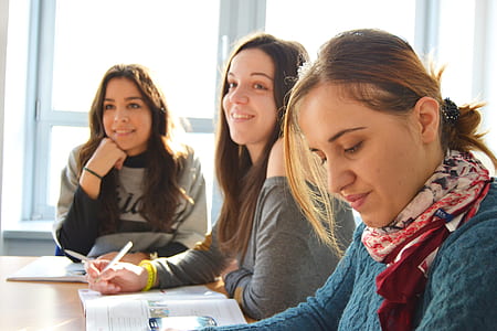 three woman holding pen with books on table thumbnail