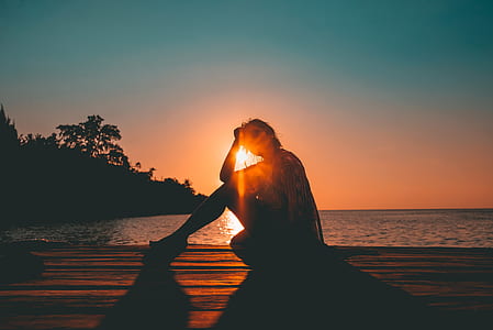 silhouette photo of person sitting on beach thumbnail