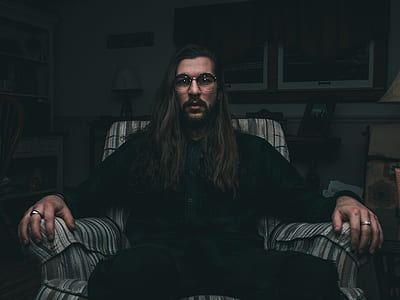 man wearing black shirt and sitting on chair thumbnail