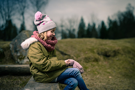 girl holding gloves while sitting in wooden bench thumbnail
