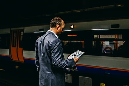 person reading newspaper while waiting for train thumbnail
