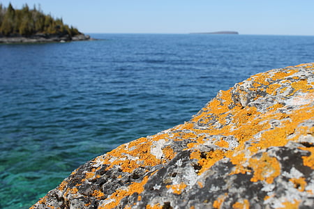 brown and gray rock beside calm body of water thumbnail