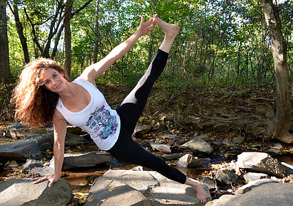 woman wearing white tank top Stretching legs  on top of gray rock thumbnail