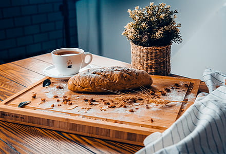 bread beside white ceramic teacup on brown wooden board thumbnail