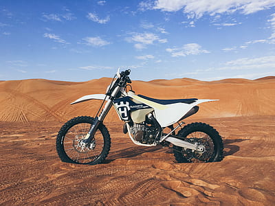 white and black Husqvarna dirt bike on desert taken during daytime thumbnail