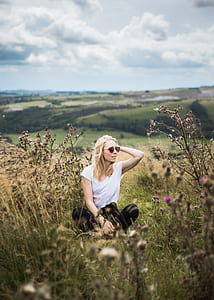 woman sitting on grass surrounded by flowers during daytime thumbnail