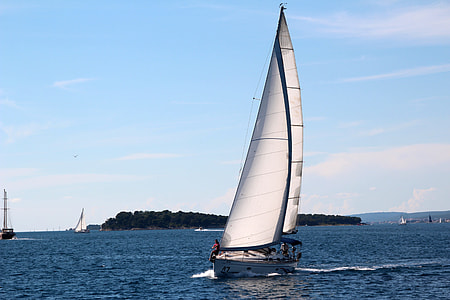sailboat at the ocean near island and sailboats during day thumbnail