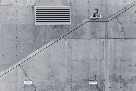woman standing leaning on staircase in grayscale photo thumbnail