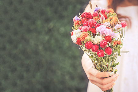 tilt shift lens photography of  yellow, pink, and red flower bouquet held by girl thumbnail