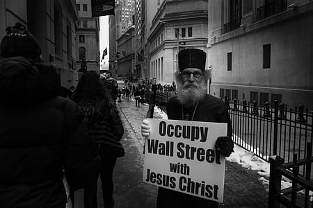 man wearing black shirt holding white boar with Occupy Wall Street with Jesus Christ poster thumbnail