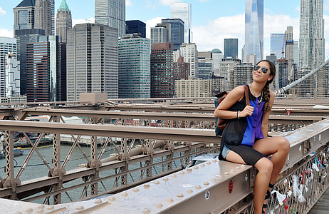 woman in blue and black tank top sitting on bridge near high rise building under water thumbnail