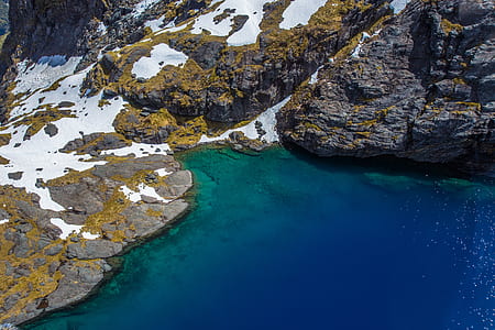 gray stone with snow near body of water thumbnail