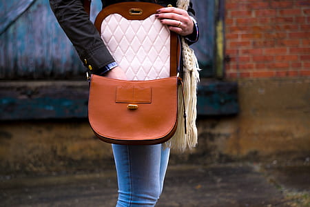 woman putting hands inside brown leather sling bag thumbnail