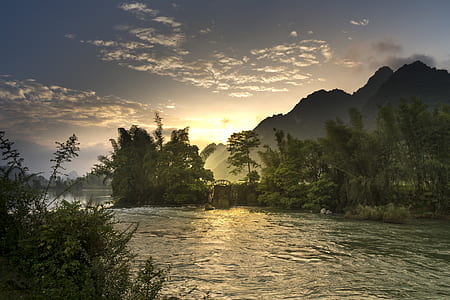 body of water in between forest during golden hour photo thumbnail