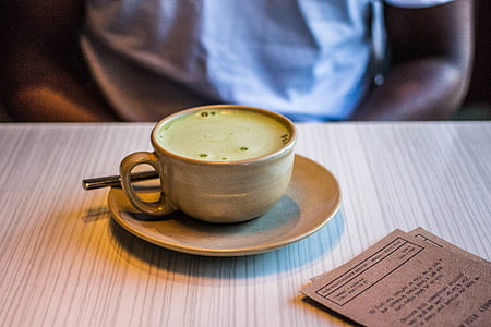 person sitting in front of coffee mug filled with green liquid on table thumbnail
