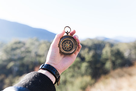 person holding gold-colored compass thumbnail