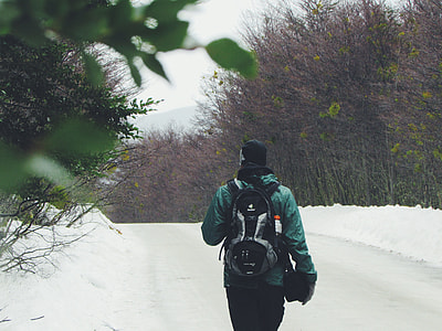 shallow focus photography of person in green winter jacket walking on snow covered field during nighttime thumbnail