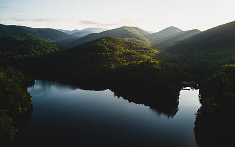 calm body of water near green mountain at daytime thumbnail
