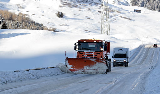 red snow plow truck running on road with white Renault van on back at day thumbnail