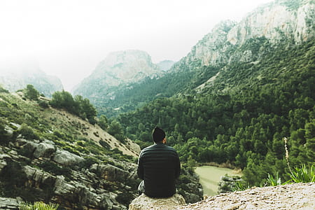man sitting on rock on mountain during daytime thumbnail
