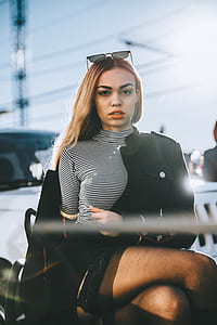 selective focus photography of woman wearing black-and-white stripe turtleneck shirt and black jacket near white Jeep Wrangler SUV at daytime thumbnail