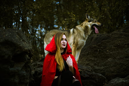 woman wearing red cloak with standing wolf behind thumbnail