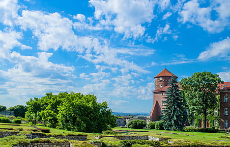 white cumulus clouds over bricked palace with surround green trees during daytime thumbnail