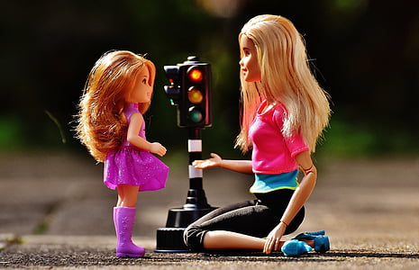 Barbie doll in front of baby doll in the middle of street thumbnail