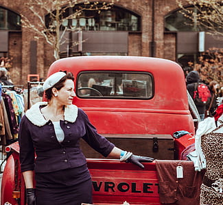 woman standing behind red Chevrolet pickup truck thumbnail