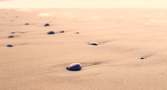 blue stones on sand during daytime thumbnail