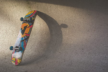 Multicolored Skateboard Leaning on Wall thumbnail
